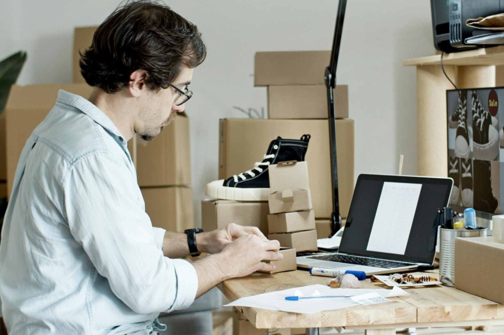 Person attaching a label to a box on a desk and with packaging materials