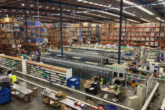 Automated warehouse fulfillment center with conveyor systems and shelving.
